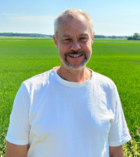 Ola Pettersson, projektledare har vit t-shirt på sig och står vid ett fält