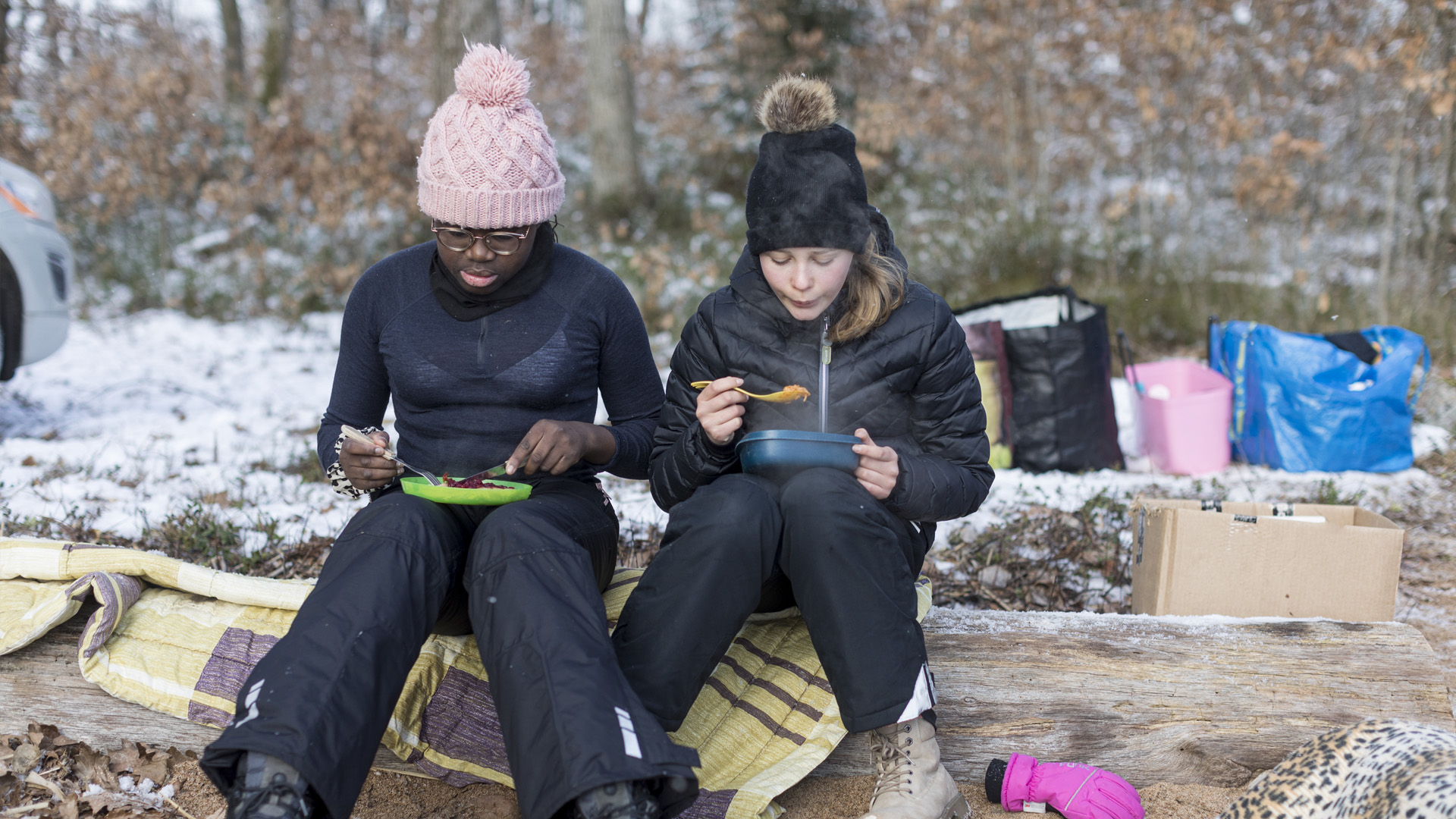 Två elever äter lunch utomhus en vintrig dag.