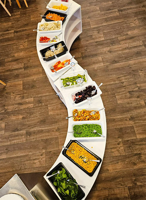 Salladsbuffé fotograferad uppifrån, med massa olika skålar med grönsaker