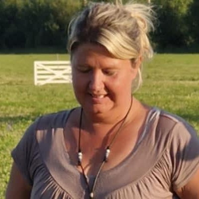 Lisa Nes har en beige tröja och jeans där hon står utomhus i gräset