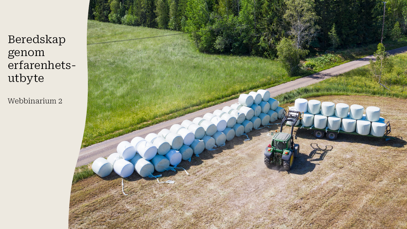 Vy över ett fält där en traktor lastar ensilagebalar