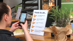 En kvinna fotograferar av ett faktablad om vilka effekter svensk ost på pizzan kan ge