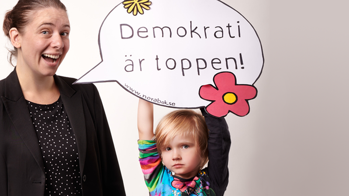 Marléne och ett barn som håller upp en pratbubbla där det står texten Demokrati är toppen.