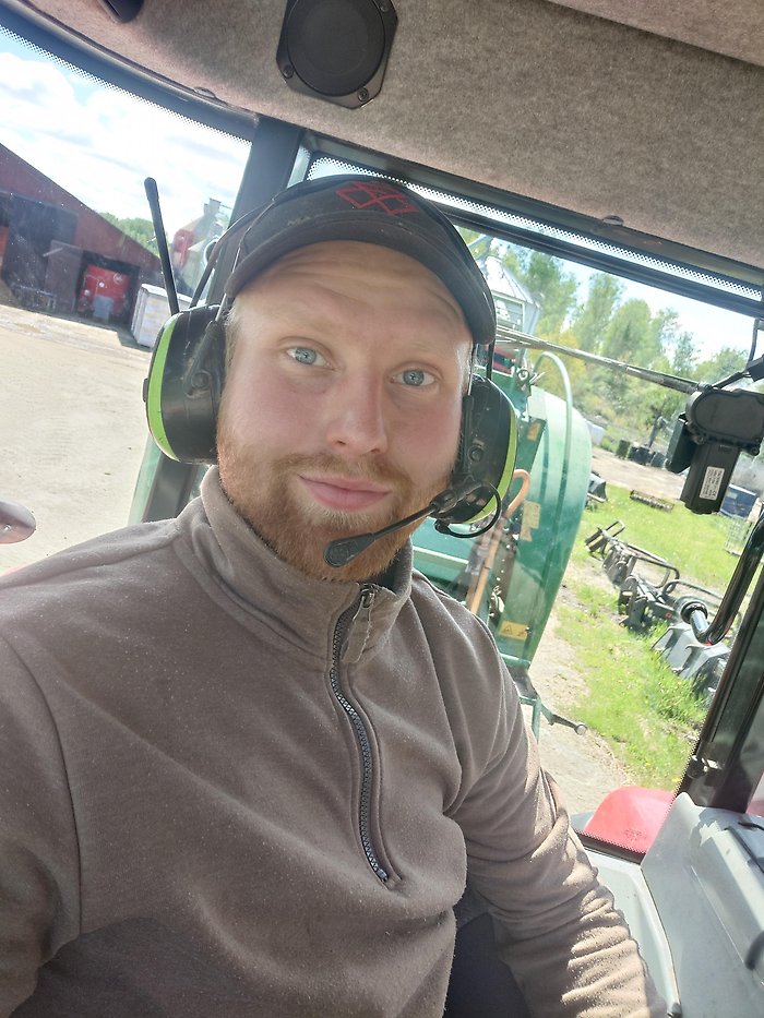 Nils Gustawson sitter i förarhytten på traktorn