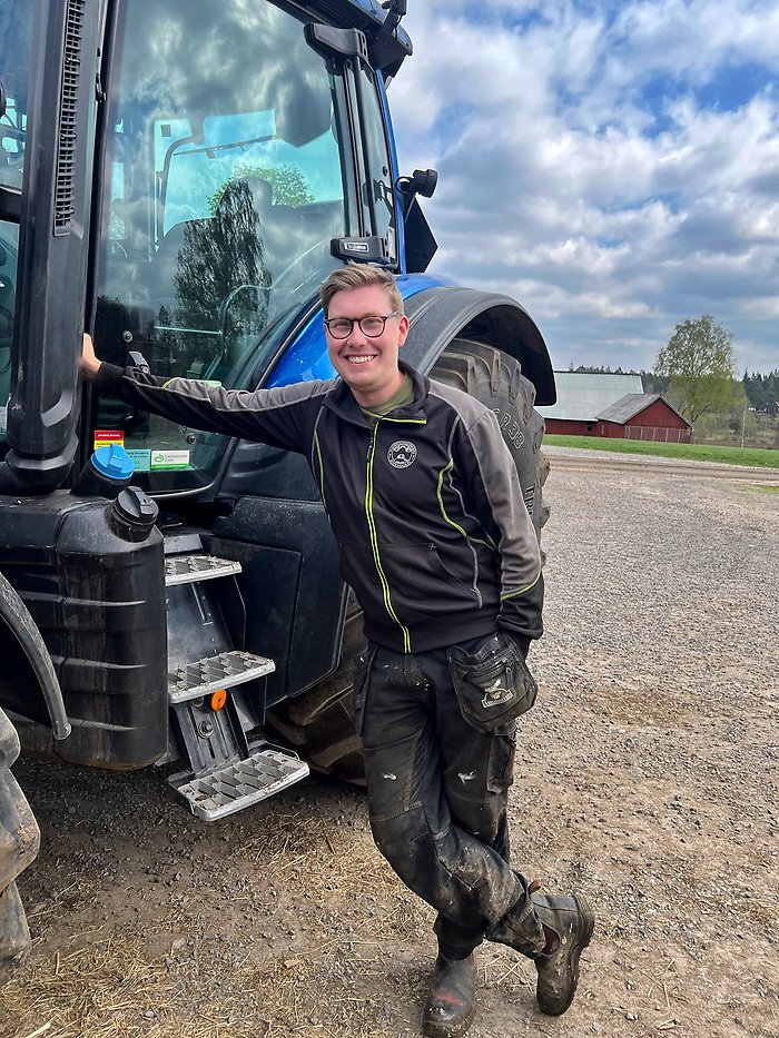 Lucas Bertilsson vid sin blå traktor