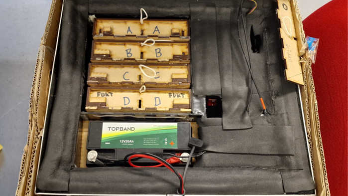 En klimatbox där man ser fyra kassetter för bidrottningar och puppor och ett batteri