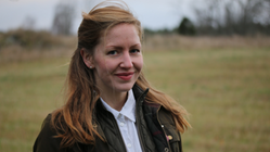 Stephanie Kindbom arbetar på Jordbruksverket och är ledamot i Landsbygdsnätverkets arbetsgrupp Kunskaps- och innovationsfrämjande i gröna näringar. Hon har rött hår, vit skjorta och brunjacka.
