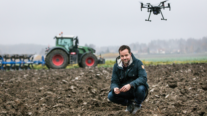 Jonas Engström Jadvi har mörka kläder på sig och sitter framför en röd traktor på en åker