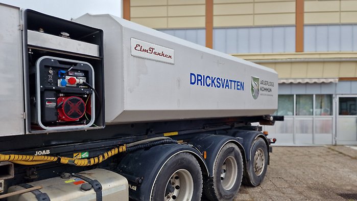 En stor dricksvattentank på ett lastbilssläp. Kommunens logotyp finns på tanken.
